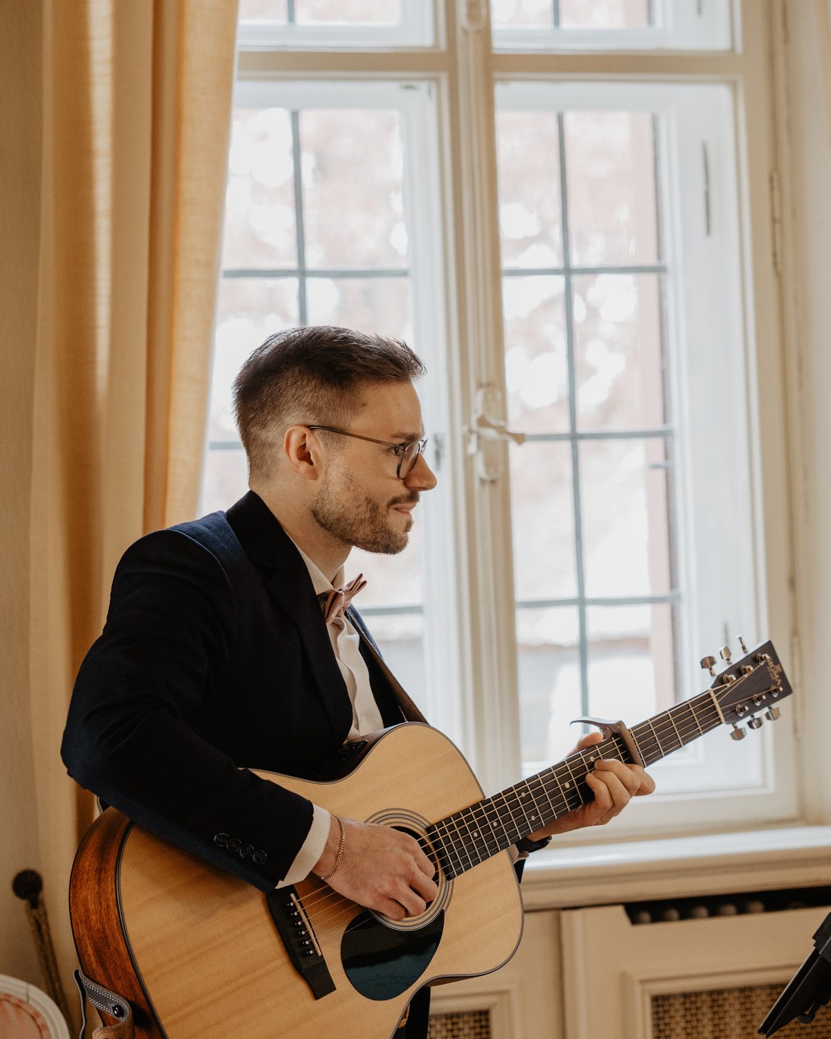 Andy Elscheid spielt Gitarre im warmen Fensterlicht